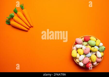 Colorful Easter eggs in the basket on orange background with four carrot. Spring holidays concept Stock Photo