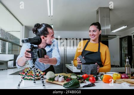 latin couple blogger vlogger and online influencer recording video content on mexican food in the kitchen in Mexico city Stock Photo