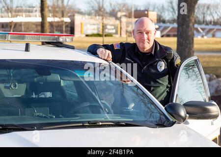 A Purdue University Fort Wayne police officer stands next to a patrol car on campus. Stock Photo