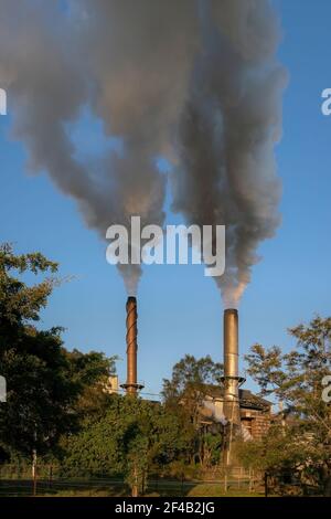 Emissions rise up out of two smoke stacks Stock Photo