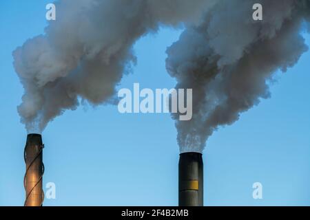 Smoke and steam rise up from two chimneys Stock Photo