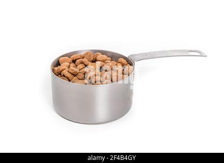 Kibbles in measuring cup. Dry dog food portioned out for a medium to large dogs meal time. Heap of brown pet food pellets in a 1 cup stainless steal Stock Photo Alamy