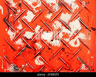 Used paint tray with multiple old paint colors stuck on diamond plate pattern. Top view of many times reused red plastic paint pan. Rough grunge textu Stock Photo