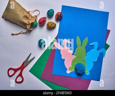 scissors on blue background easter hares with tail and eggs Stock Photo