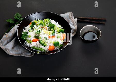 Fresh and healthy vegan rice bowl served with broccoli, carrot and spring onion with chopsticks on the side Stock Photo