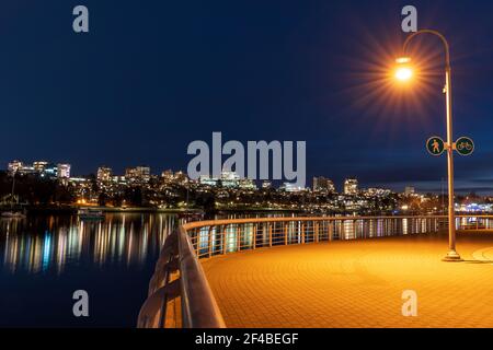 Pedestrian and bicycle shared route sign and pathway at night. Vancouver downtown Seaside Greenway coastal area walking path. Stock Photo