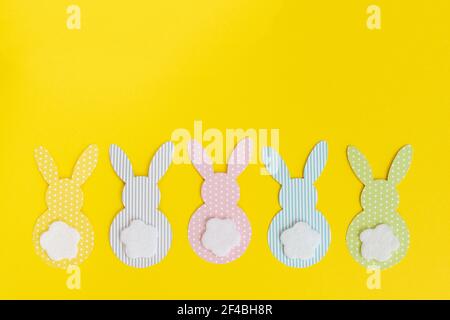 Easter paper bunnys isolated on yellow background. DIY holiday handicraft decoration of colorful rabbits. Concept: children's crafts for Easter. Top v Stock Photo