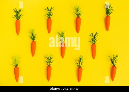 Easter pattern made with carrots on bright yellow background. Minimal Easter composition. Flat lay. Stock Photo