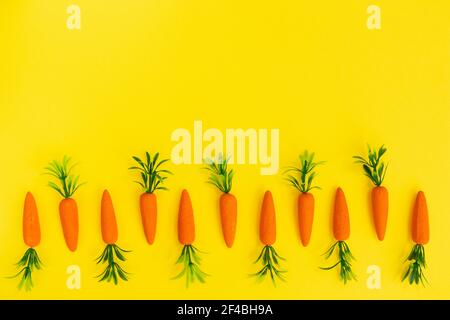 Easter pattern made with carrots on bright yellow background. Minimal Easter composition. Flat lay. Stock Photo