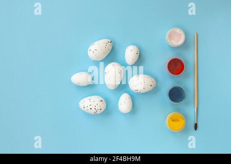 Easter symbols. Set of decorative eggs, multi-colored paints and brushes on blue background top view, flat lay. Preparation for holiday. Easter entert Stock Photo