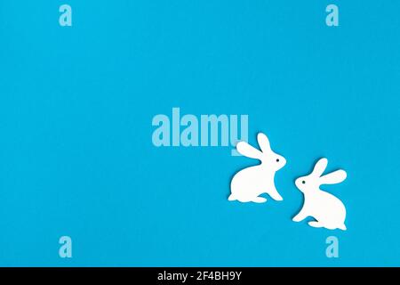Happy Easter. Congratulatory easter background. Two white Easter bunny on blue background. Minimal Easter concept. Stock Photo