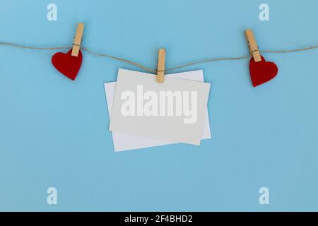 Envelope and red hearts, hanging on line against blue background. Valentines Day decoration. Stock Photo