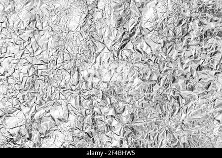Texture of crumpled aluminum kitchen foil. Silver foil with shiny surface for background. Top view closeup. Stock Photo