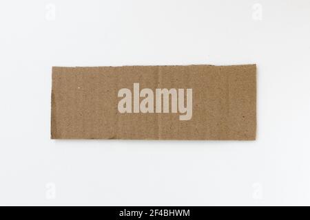 Ripped piece of cardboard isolated on white background. Cardboard with torn edges, top view. Stock Photo