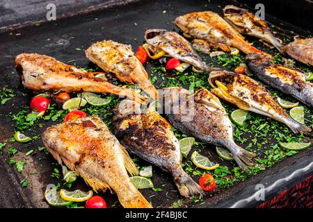 fried fish seasoned with lemon and tomatoes Stock Photo