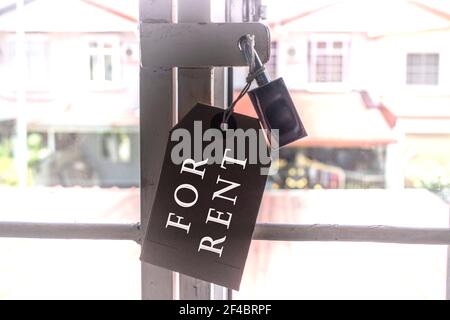 Text on tag hanging on the window grill with blurred background of houses Stock Photo