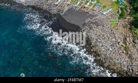 Top down aerial of traditional jukung boats resting on beach in Bali. Amed beach in Bali Indonesia with Jukung fishing boats lined up on the shore Stock Photo