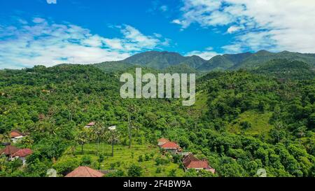 Traditional Balinese houses with panoramic view at jungle, tropical rain forest and mountains. Drone Photo of bungallows. Houses in the tropical Stock Photo