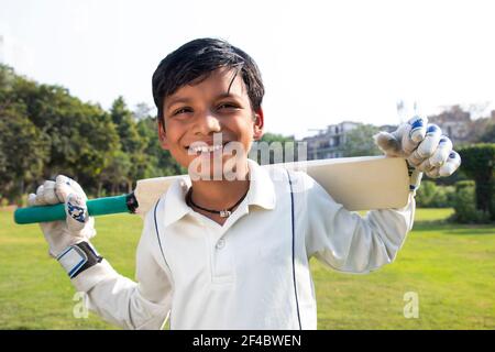 Boy in cricket uniform holding a cricket bat Stock Photo