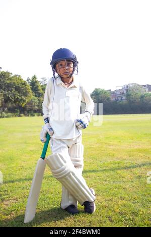 Boy in cricket uniform holding a cricket bat Stock Photo