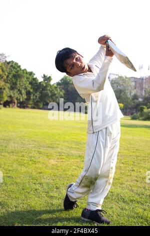 Young boy batting in protective gear during a cricket Stock Photo