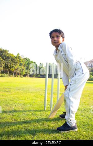 Young boy batting in protective gear during a cricket Stock Photo