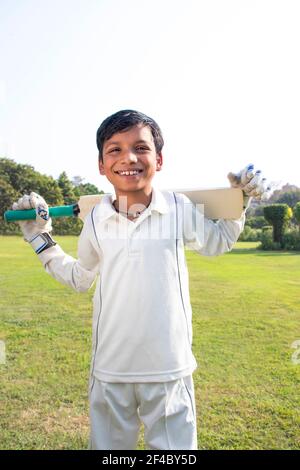 Boy in cricket uniform holding a cricket bat Stock Photo
