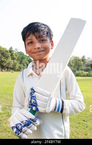 Boy in cricket uniform holding a cricket bat Stock Photo