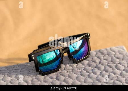 Pixel sunglasses model with blue lenses and black frame closeup in a sunny day. Selective focus Stock Photo