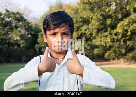 A boy in cricket uniform and pointing Stock Photo