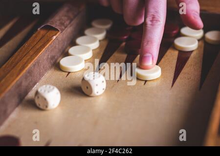 Playing backgammon game. Man´s hand move gammon on board game. Dice on wooden board Stock Photo