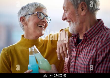 A happy elderly couple enjoying a drink and time spending together in a cheerful atmosphere. Spouses, elderly, together Stock Photo