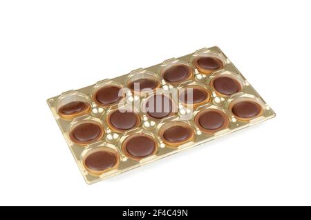 Salted caramel round candy close-up isolated on white background. Milk chocolate candies in plastic golden tray Stock Photo