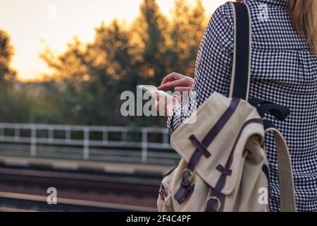 Woman using phone on railroad station. Traveler using smart phone during waiting for train. Stock Photo