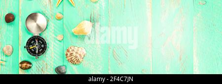 Seashells and compass on blue wooden table background. Summer vacation background, vacation and travel concept. Stock Photo