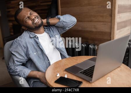 Portrait of a business young multiracial businessman massaging his neck while suffering from pain. An emaciated African man with health problems Stock Photo