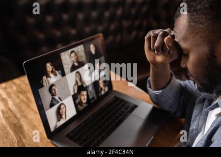 Exhausted tired African American businessman sitting at work desk with closed eyes, falling asleep, overworked young man, unmotivated student sleeping Stock Photo