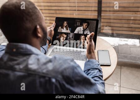 Back view. African-American worker discusses brainstorming video call with various colleagues, screen view of racial colleagues conducts team Stock Photo