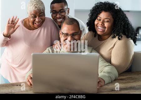 Happy black family having fun doing video call using laptop at home during corona virus outbreak - Technology and communication concept Stock Photo