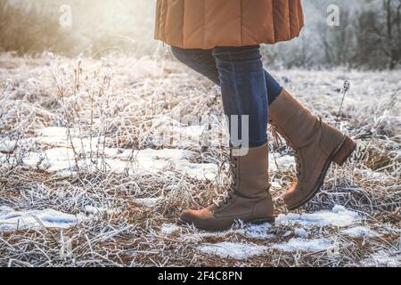 Woman wearing leather hiking boots in winter frozen nature. Walking in snowy footpath Stock Photo