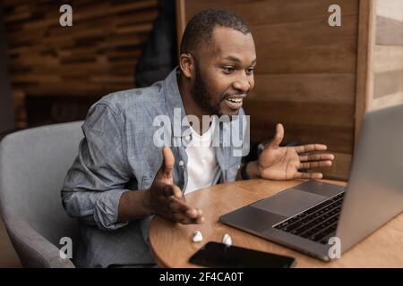 African american freelancer is using laptop, having a video conference. Handsome businessman talking with coworkers on online meeting, discuss Stock Photo