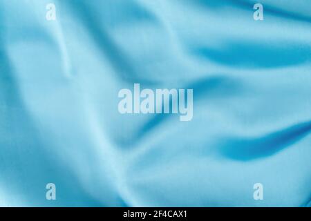 Blue silk fabric defocused for background. Abstract blur satin fabric. Elegant sky color background material with silky satin folds of cloth design Stock Photo