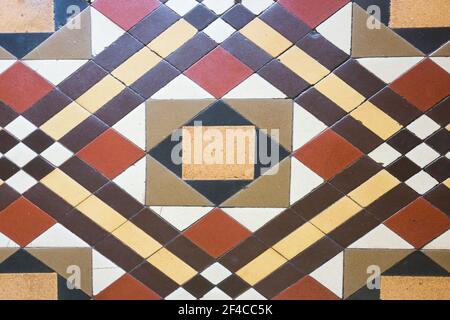 Old Victorian era tiles in a geometric pattern of rust brown cream white yellow black at the entrance to an old store in a country town in Queensland, Stock Photo