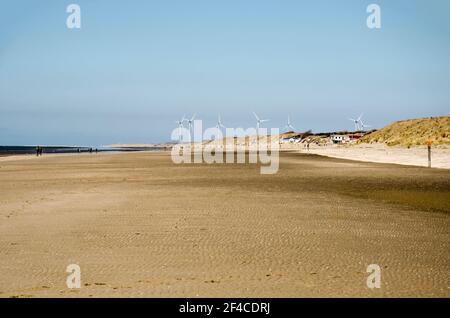 Solitude at the beach of Rockanje on the island of Voorne, The Netherlands on a sunny day in early spring with a group of large wind turbines in the d Stock Photo