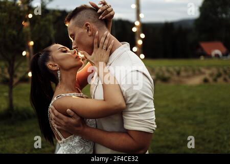Portrait of beautiful elegant couple kissing. Handsome man hugging attractive woman, enjoy tenderness. Gorgeous lady with attractive male walking at Stock Photo