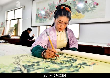 Juye, Juye County. 20th Mar, 2021. A worker draws a peony-themed realistic painting at a painting professional cooperative in Qilin Township, Juye County, Heze City of east China's Shandong Province on March 20, 2021. Heze is noted as one of the key origins of the peony flowers in China. Peony-themed, realistic-style painting as part of the traditional culture in Juye has now become an unique technique for local peasants to increase their income. Credit: Guo Xulei/Xinhua/Alamy Live News Stock Photo