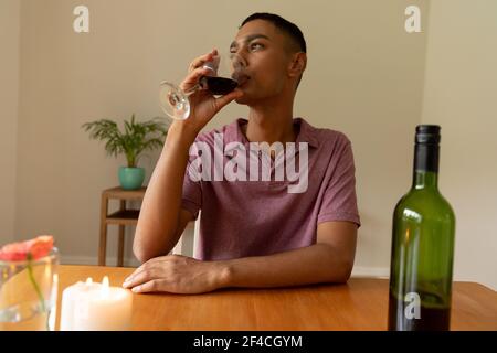 Mixed race man sitting at table and drinking wine Stock Photo