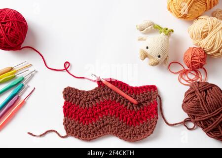 Colorful crochet project with hook and yarn, on white background. Stock Photo