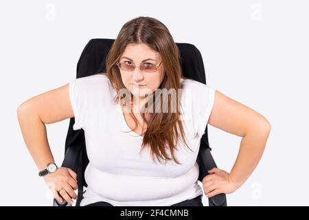 Adult overweight woman with glasses sitting on chair waiting documents file for job interview. Serious angry businesswoman Stock Photo