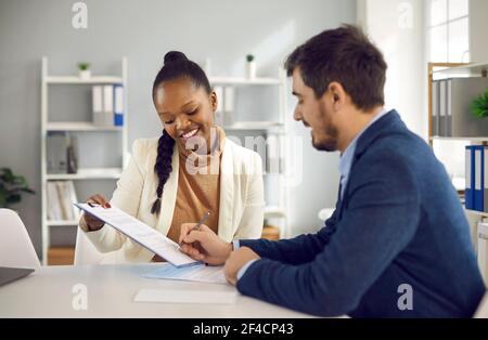 Businesswoman holding clipboard and man signing paper contract agreement Stock Photo